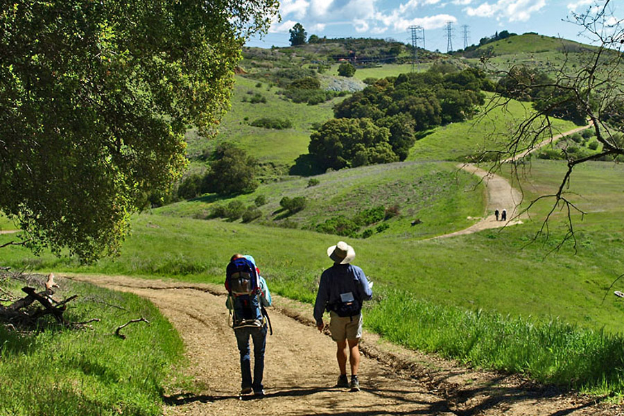 hikers hiking up a trail through the rolling green hills of Almaden quicksilver 