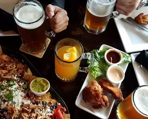Table filled with different foods and glasses of beer.